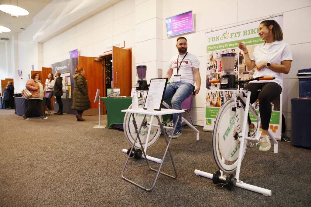Two people in white tshirts ride on stationary bikes to create power to fuel a smoothie machine