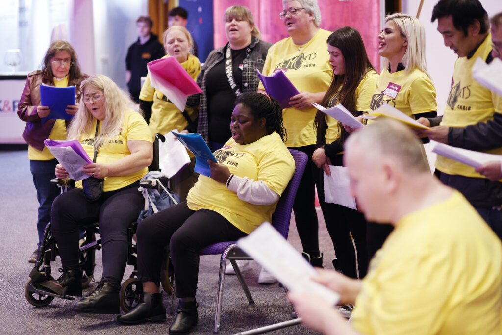 people in yellow tshirts holding papers singing in a choir
