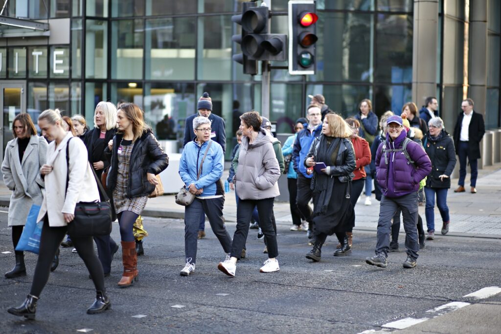 A large group of people crossing the road at a pedestrian crossing