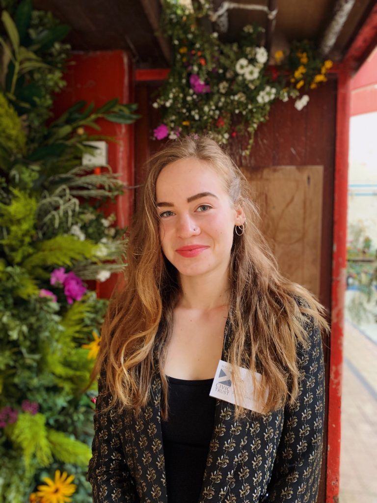 Headshot of Erin Burke, a person with long brown hair and a nose piercing.