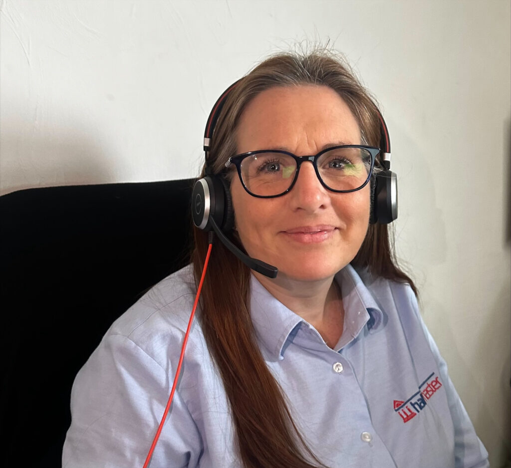 Gemma Hamilton, a white woman with brown hair and glasses wearing a headset, smiles at the camera.