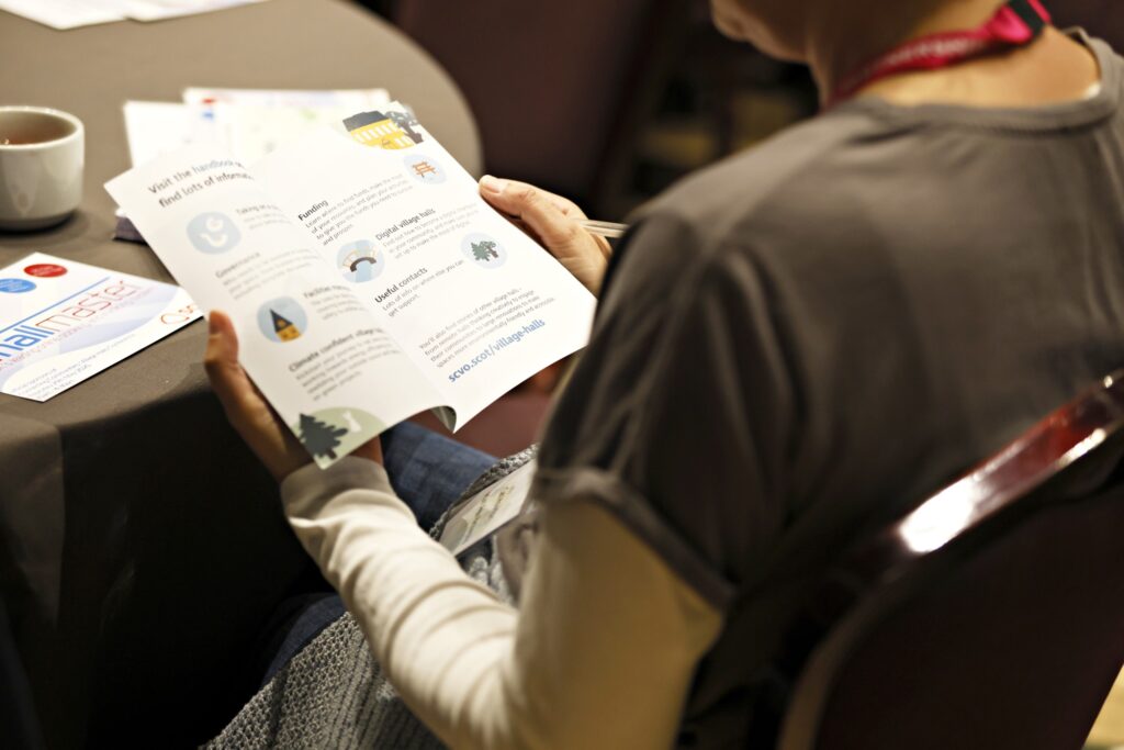 A delegate reads the promotional flyer for the Village and community halls handbook.
