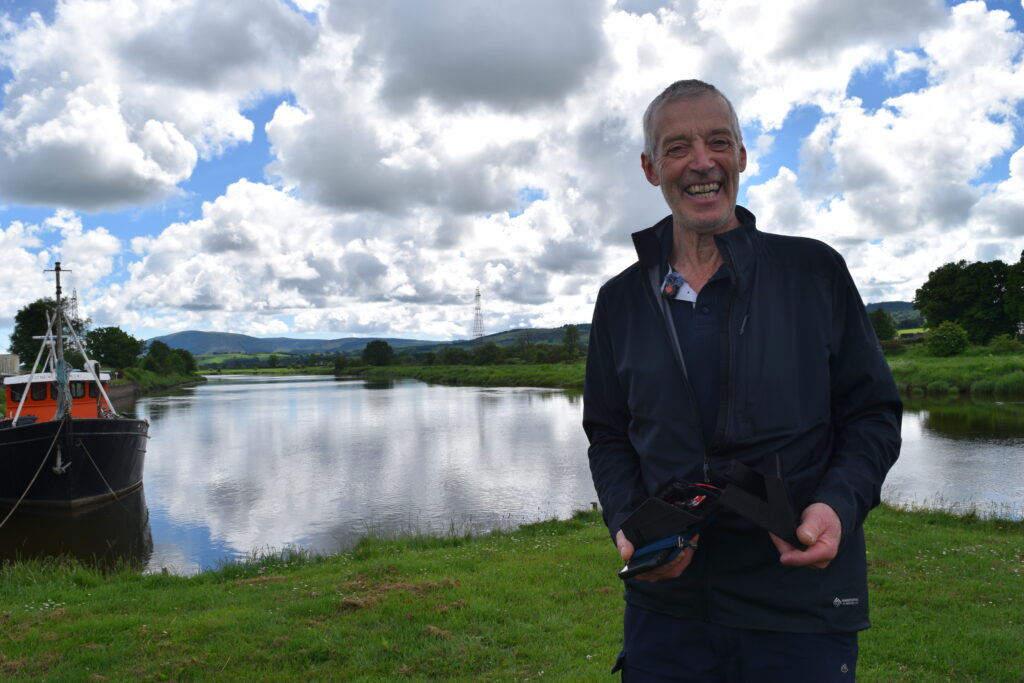 Andrew Turney holding a swift caller on the bank of the River Nith